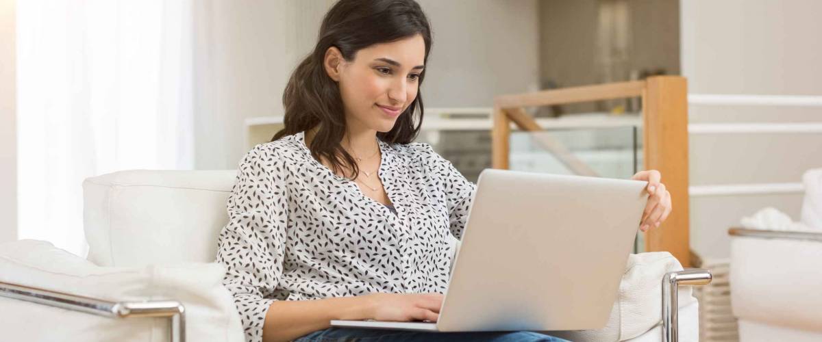 Woman with long brown hair sitting in chair and looking at large laptop computer