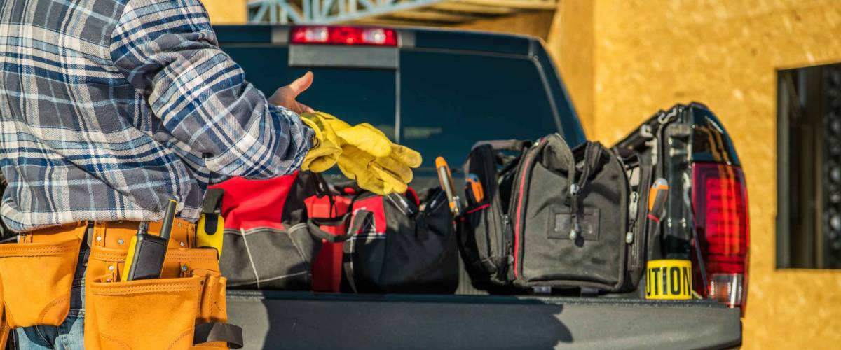 Construction Business Industry. Caucasian Contractor Worker Preparing Himself For the Job by Wearing Safety Gloves in Front of His Pickup Truck Full of Necessary Tools.