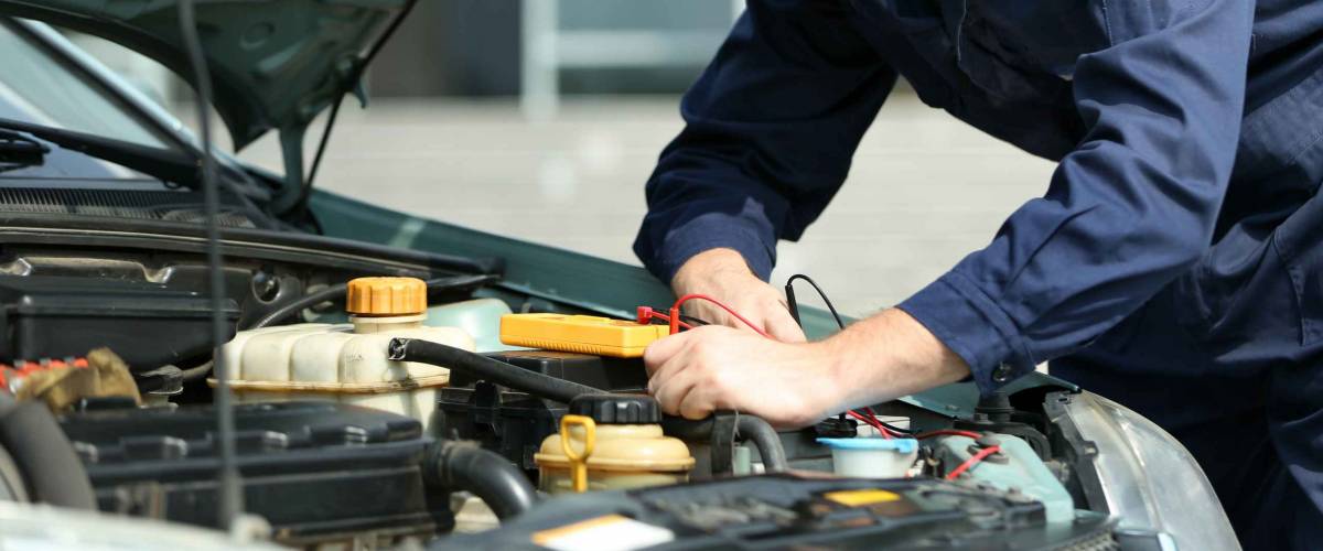 Mechanic with scan tool diagnosing car in open hood. Closeup