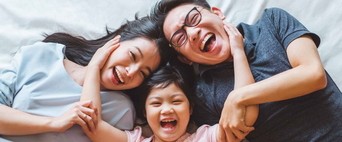 Happy Asian family laying on bed in bedroom with happy and smile, top view