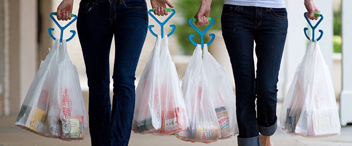 Two women in jeans carry bags of groceries using Mighty Handle