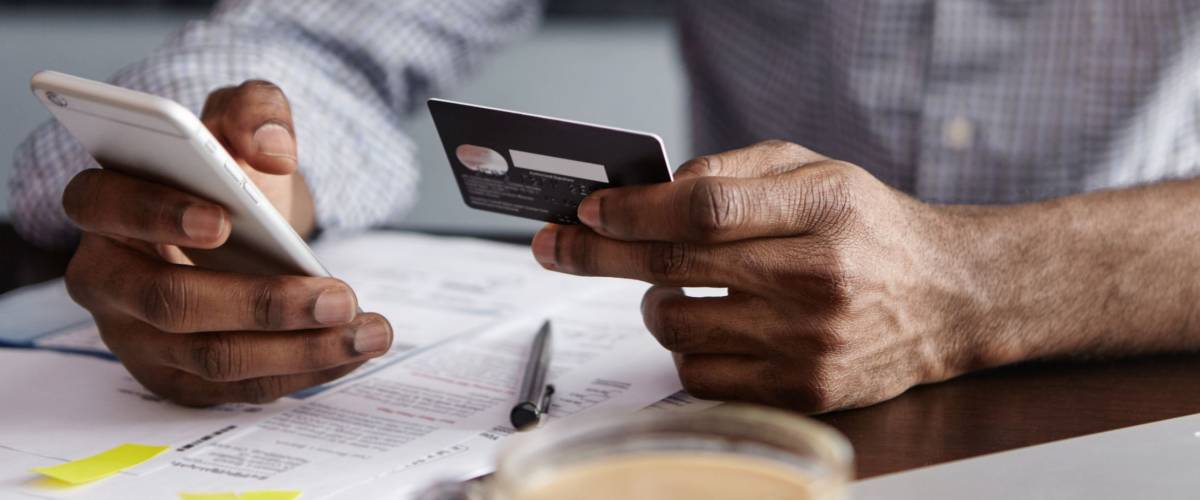 Close up shot of man's hands holding mobile phone and credit card.