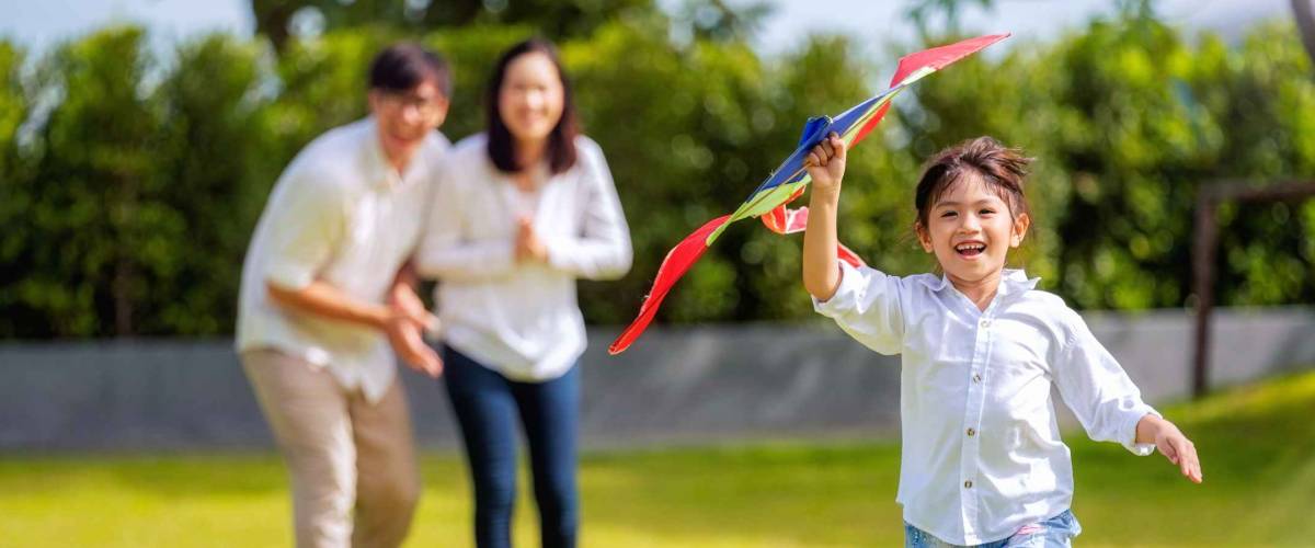 Asian family father, mother and daughter play a kite in the outdoor park in village near thay home, this image can use for family, relax, freedon, summer and travel concept