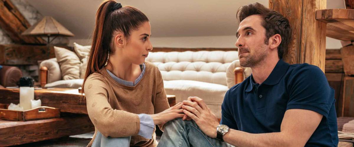 Horizontal shot of an attractive young couple talking in the living room