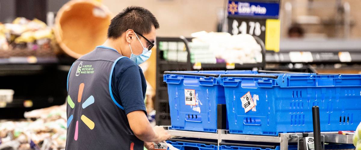 Walmart employee works inside a walmart store wearing a face mask
