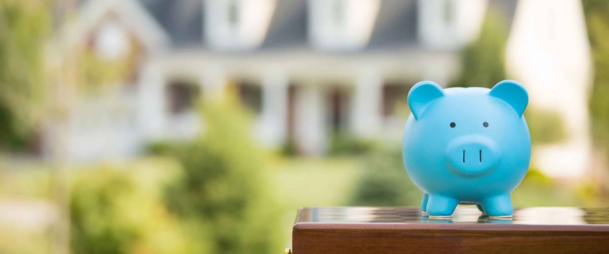 . Piggy bank isolated outside home on background. Focus on piggybank. Homeowner