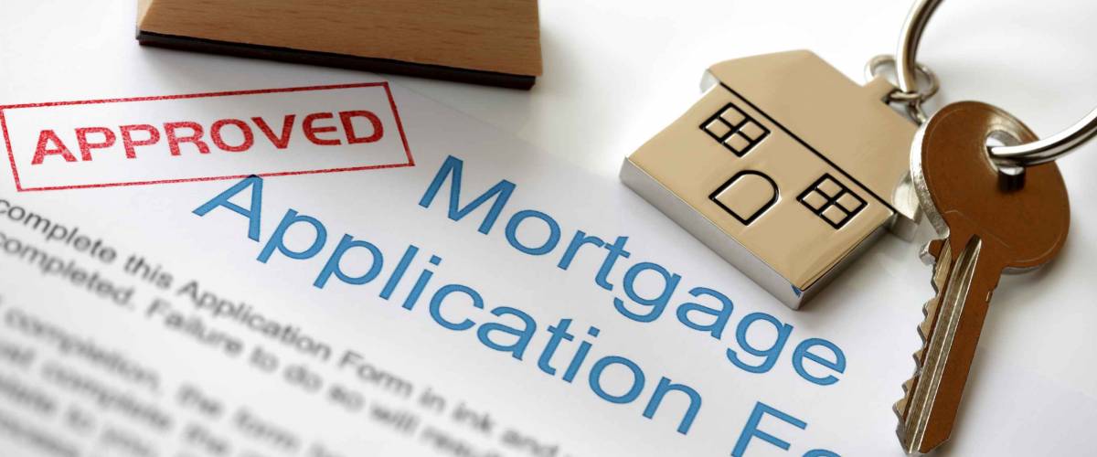 Approved Mortgage loan application with house key and rubber stamp