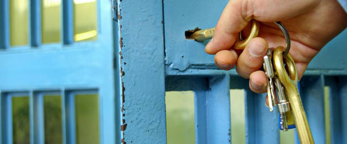 Police officers locks the door in prison corridor.