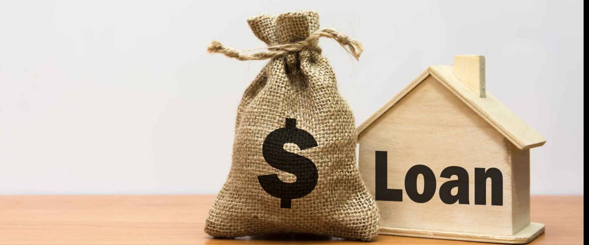 Wooden house with LOAN written on it, burlap bag with dollar sign on it