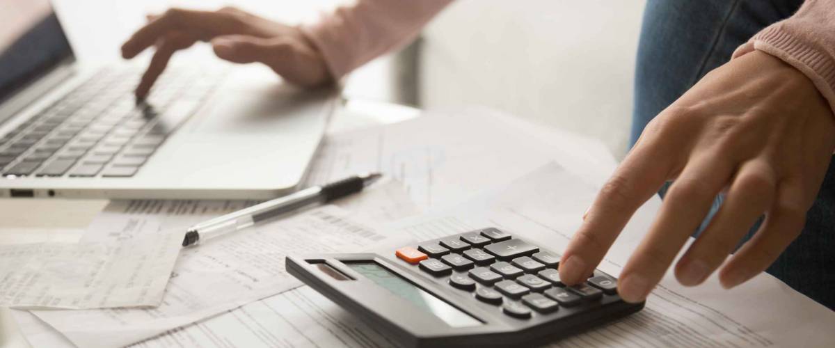 Close up of woman's hands with papers, laptop and calculator