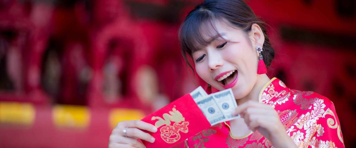 beautiful girl in the Cheongsam red dress up open the red envelope with money, in the Chinese New Year. Festivities, New Year Celebration