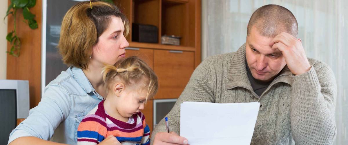 Serious couple with little girl counting budget at home