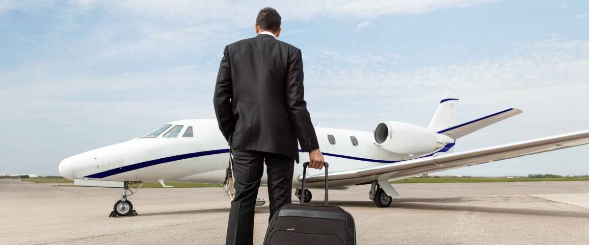 Rear view of businessman with luggage walking towards corporate jet