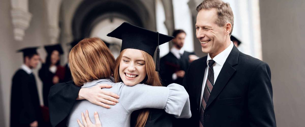 Parents congratulate the student, who finish their studies at the university. He graduates. They are very happy about this.