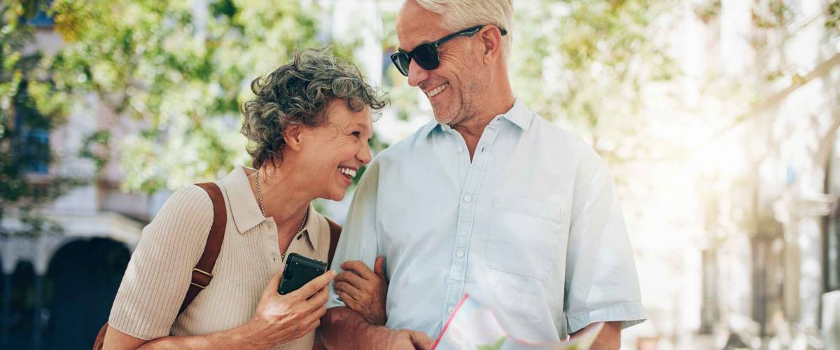 Retired couple walking around the town with a map. Smiling mature man and woman roaming around the city.