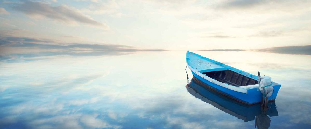 Canoe floating on the calm water under amazing sunset