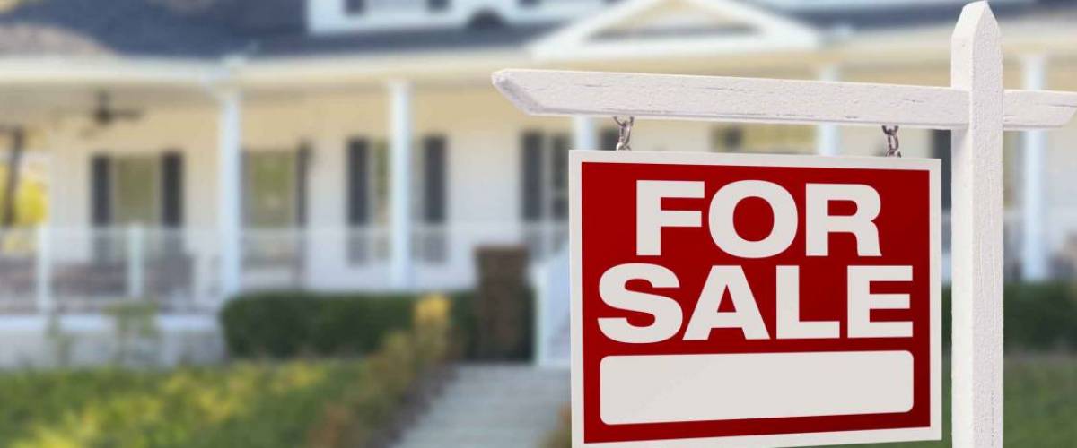 for sale sign in front of big white house