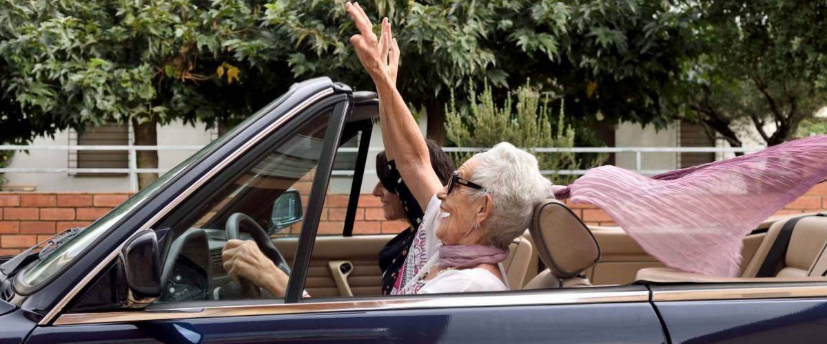 an older woman and a young woman driving a convertible