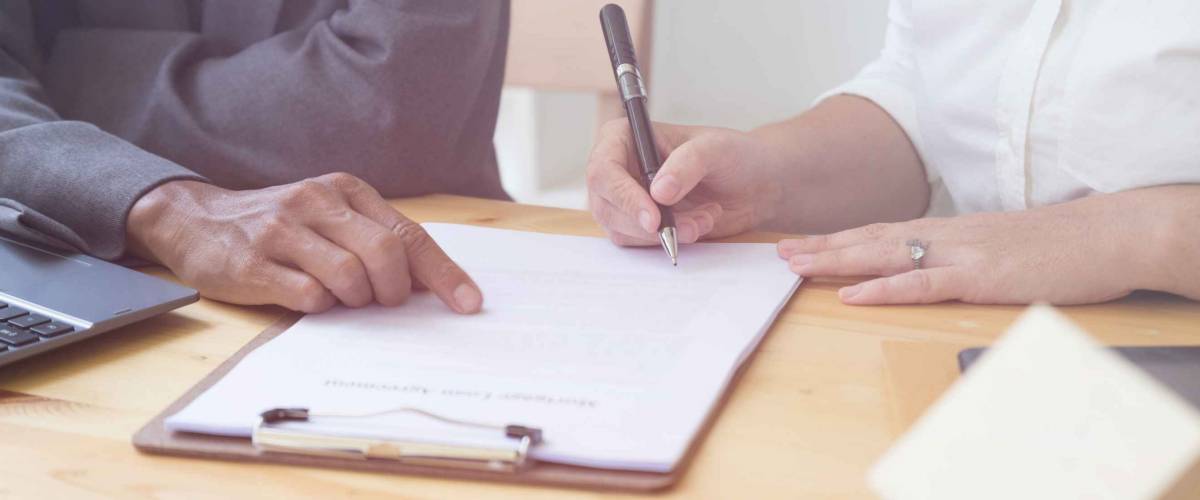 woman holds a pen over application form, while man points at form