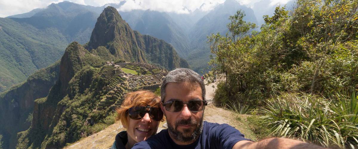 Couple taking selfie on the terraces above Machu Picchu, the most visited travel destination in Peru. Concpet of adventures in South America and people traveling aroudn the world.