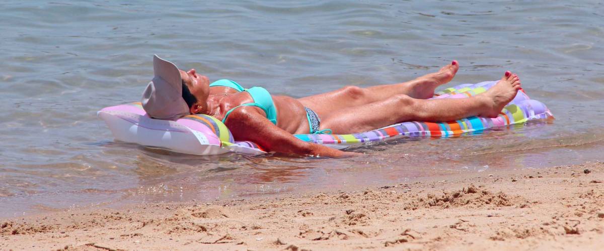 Hurghada / Egypt. 02 August 2018:elderly woman lying in swimsuit on inflatable mattress on seashore. Slender woman sunbathing on mattress by sea. Adult woman enjoying relaxing near ocean