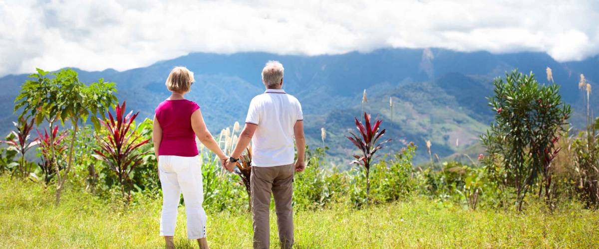 Senior couple hiking in mountains. Mature man and woman trekking in Borneo jungle. Family looking at Mount Kinabalu peak, highest mountain of Malaysia. Summer vacation in Southeast Asia.