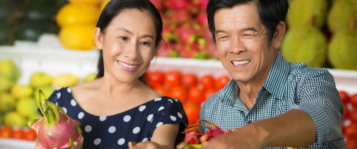 Close-up image of a senior couple buying fruits and vegetables in the market on the foreground