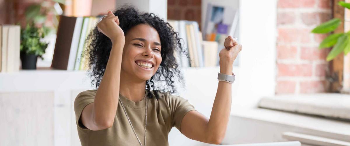 Excited african American woman sit at desk feel euphoric win online