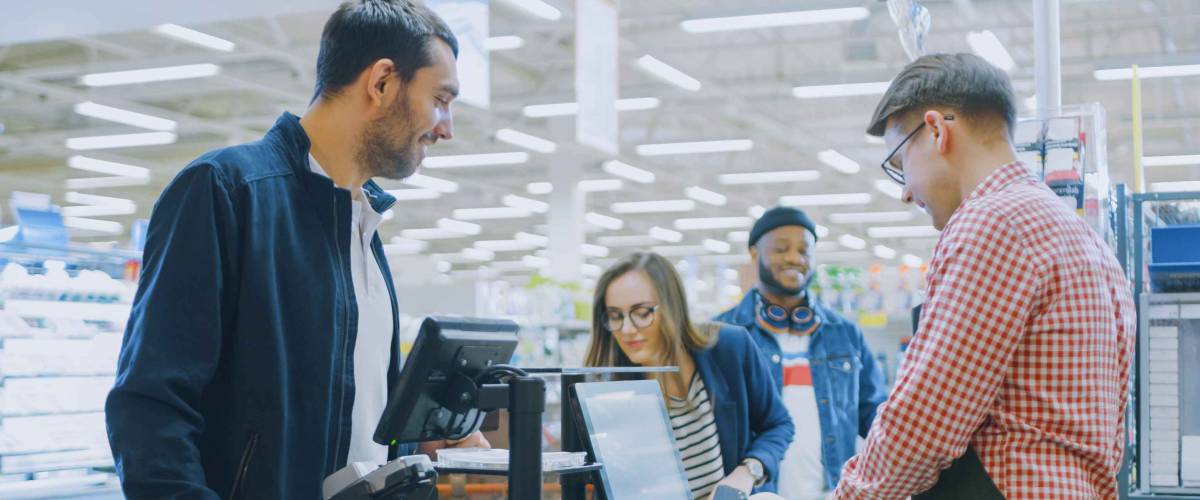 At the Supermarket: Checkout Counter Professional Cashier Scans Groceries and Food Items. Clean Modern Shopping Mall.