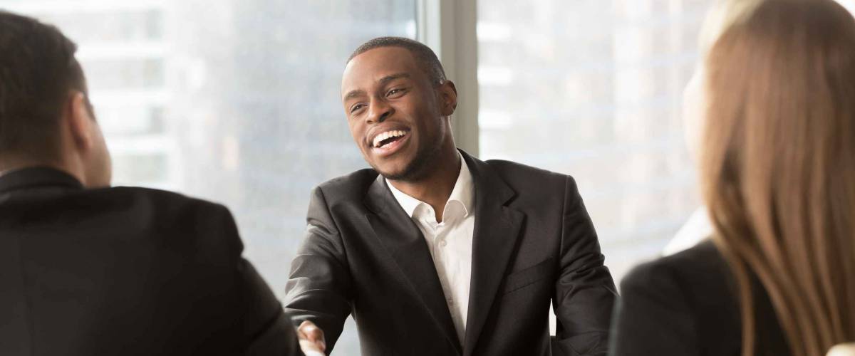 smiling man with two people facing him, shaking hands