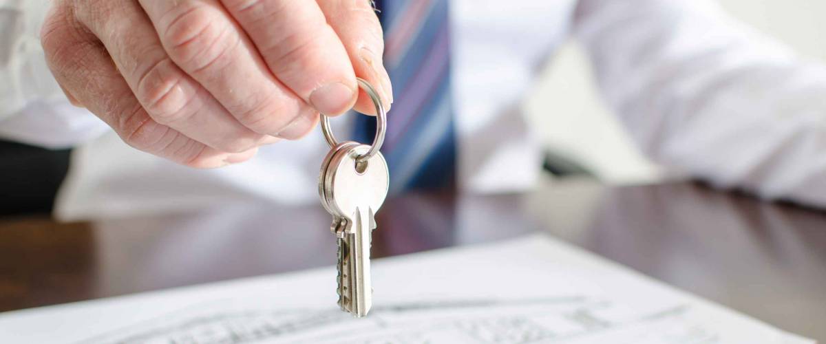 man holds set of keys over papers