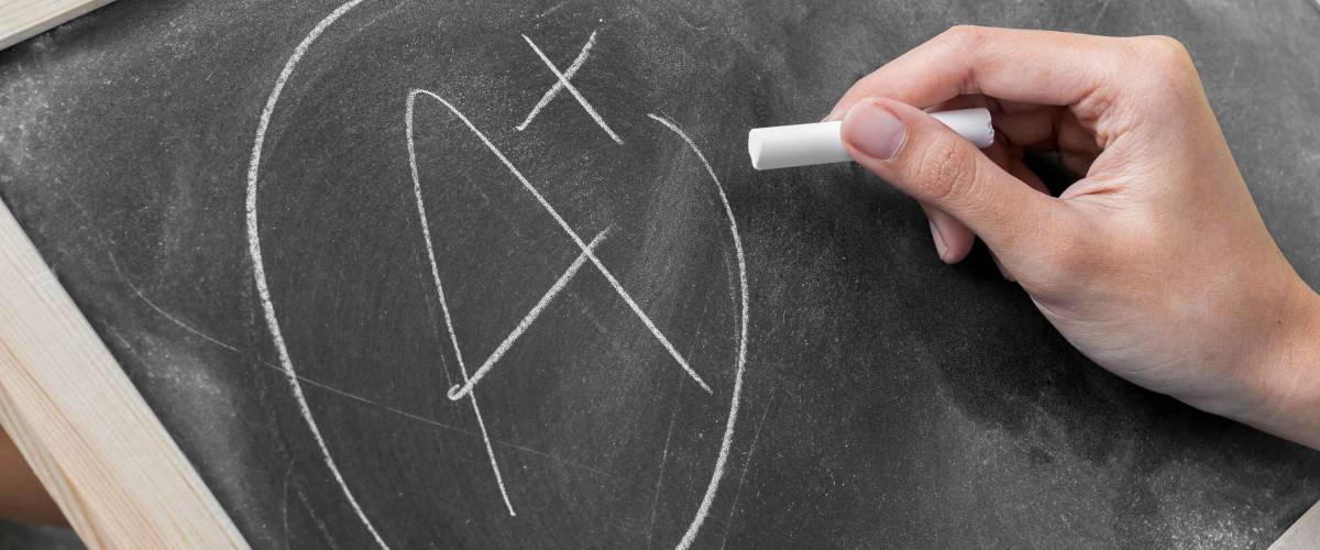 Young women write grade a plus on blackboard