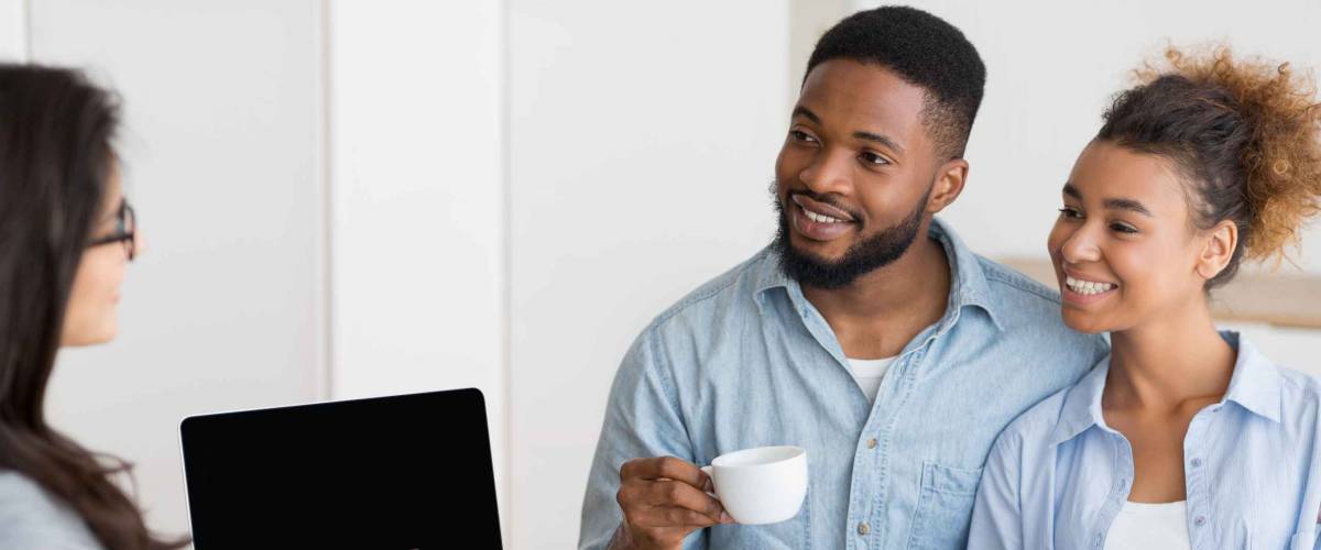 happy young couple talks to woman across a table