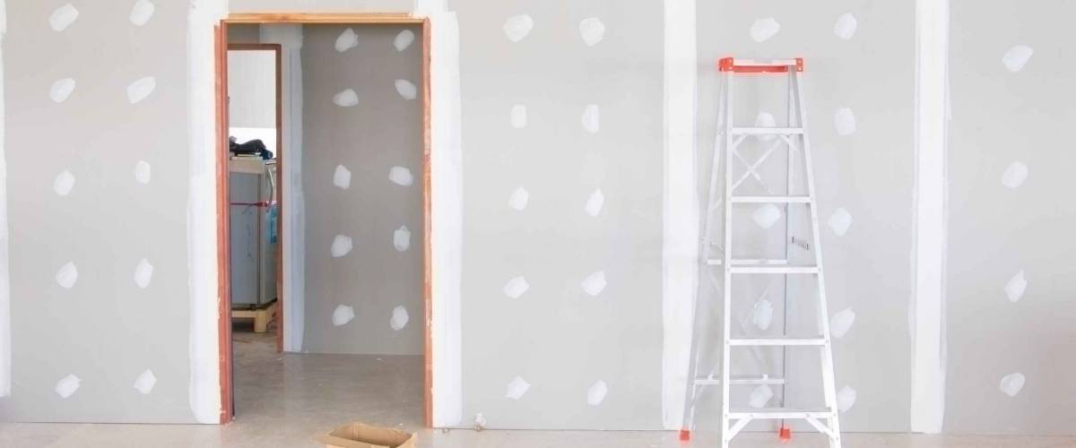 exposed gypsum and ladder leaning against wall on room under construction