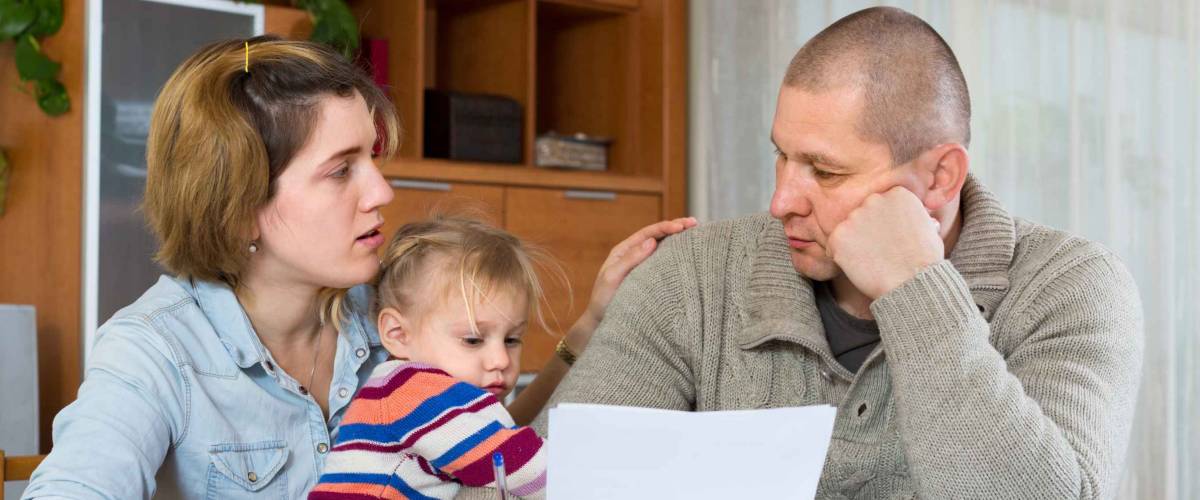 worried parents sit at table with daughter looking at paper