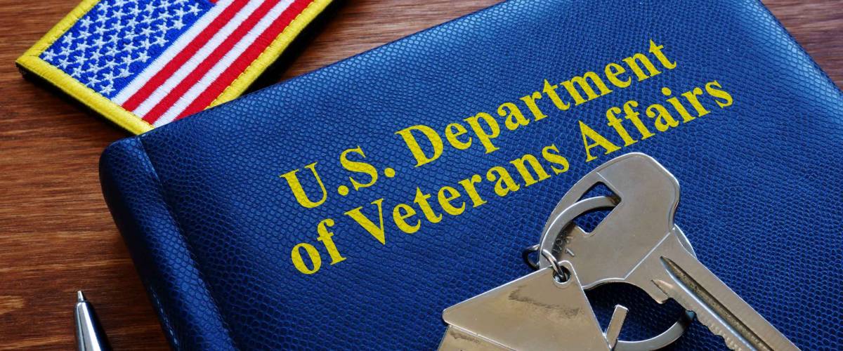 US department of veterans affairs folio with silver key laid on top, american flag patch beside it