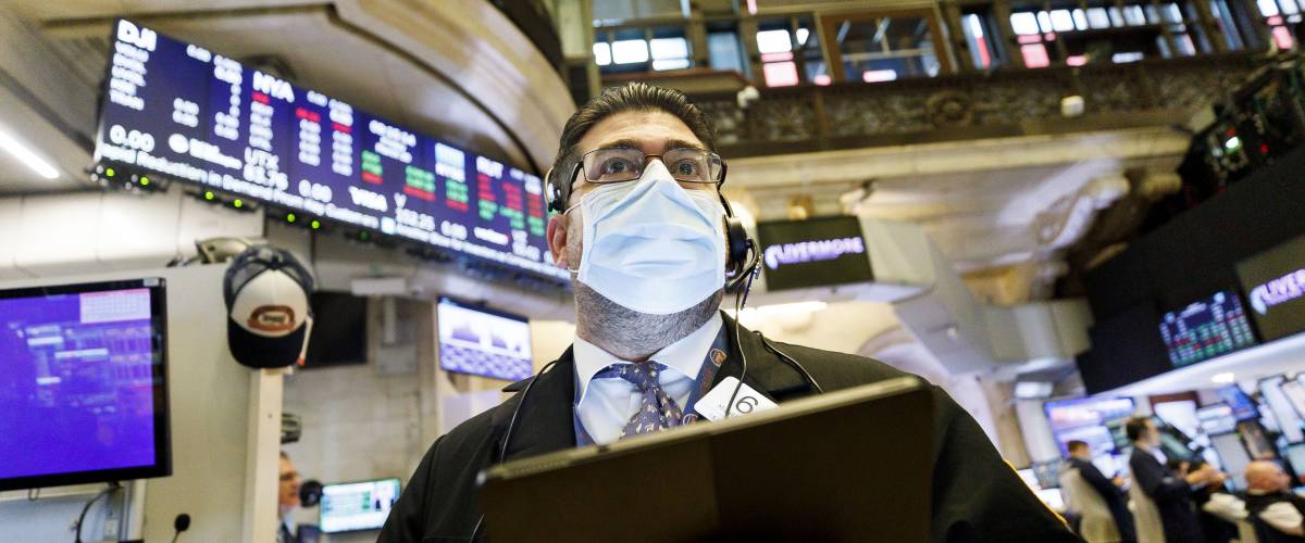 Man wearing face mask at New York Stock Exchange, holding tablet