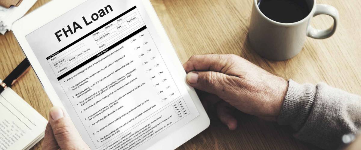 older man's hands hold form that says FHA Loan