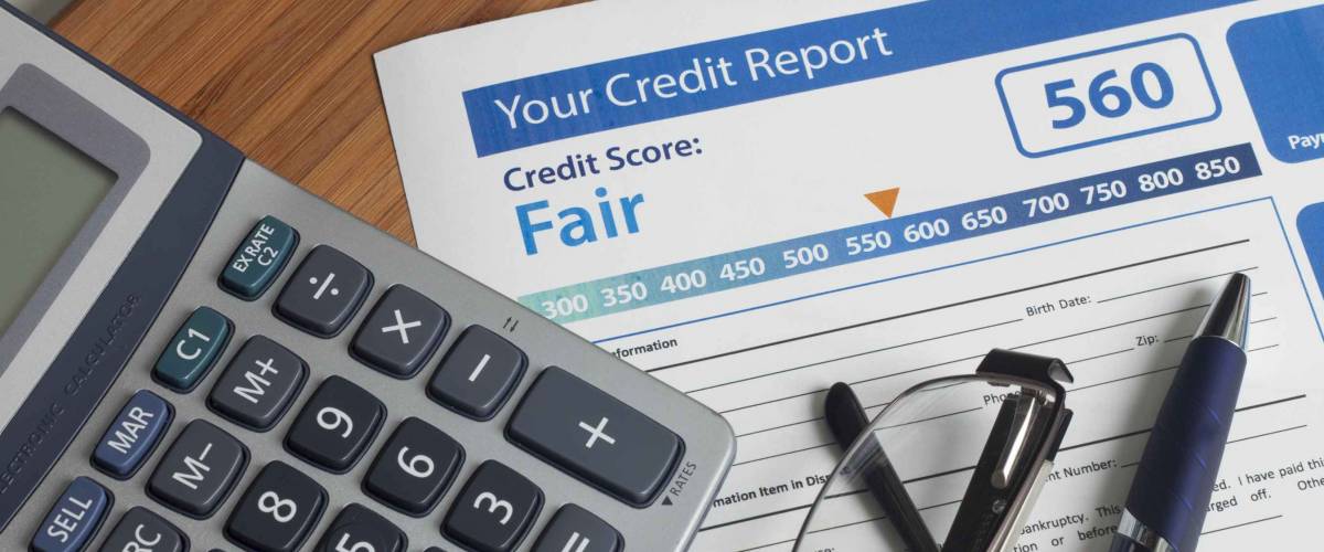 Credit report with score on a desk with glasses, pen and calculator