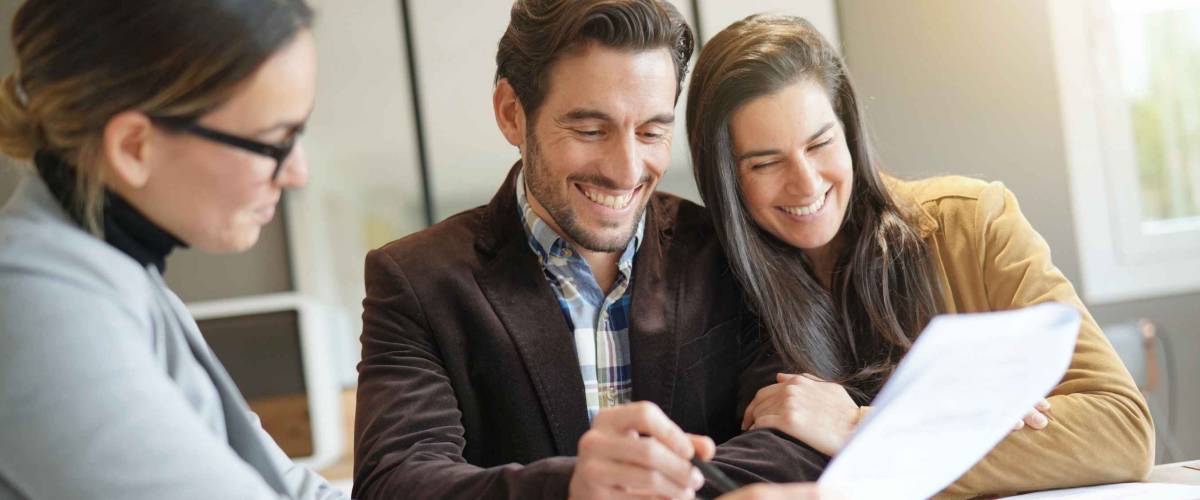 smiling couple sign paper that a woman holds up for them