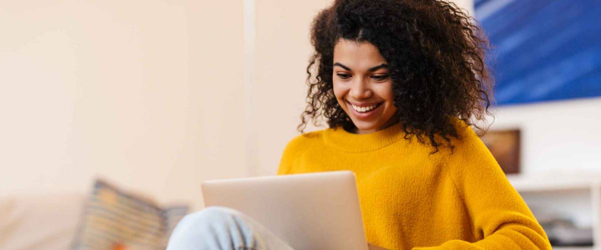 happy young woman looks at laptop while sitting in chair