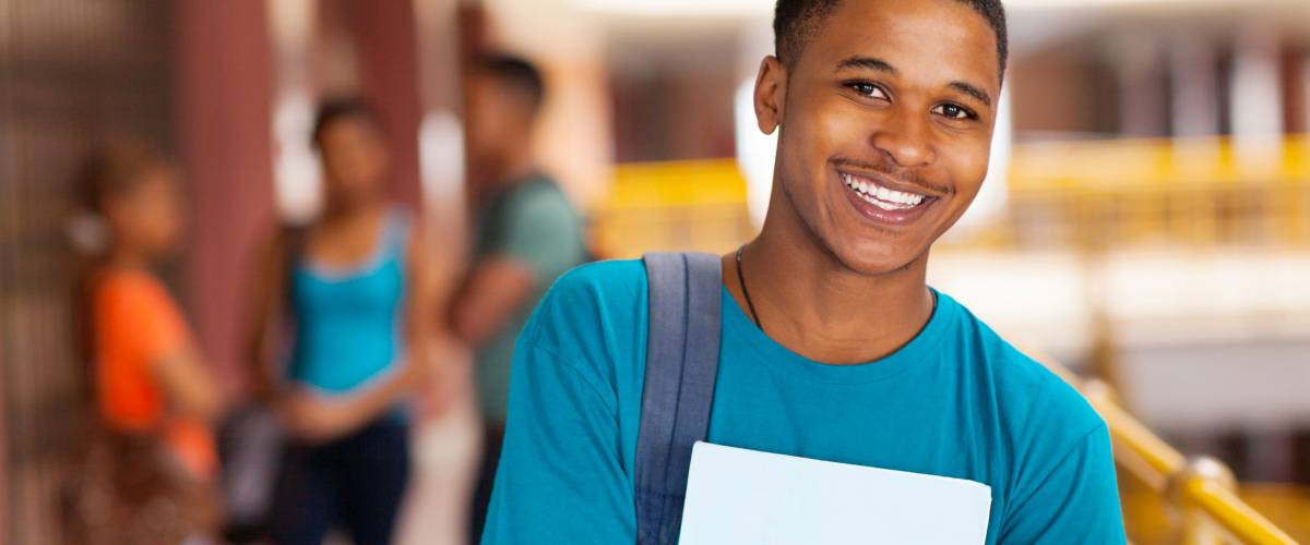 handsome young college boy holding books on campus