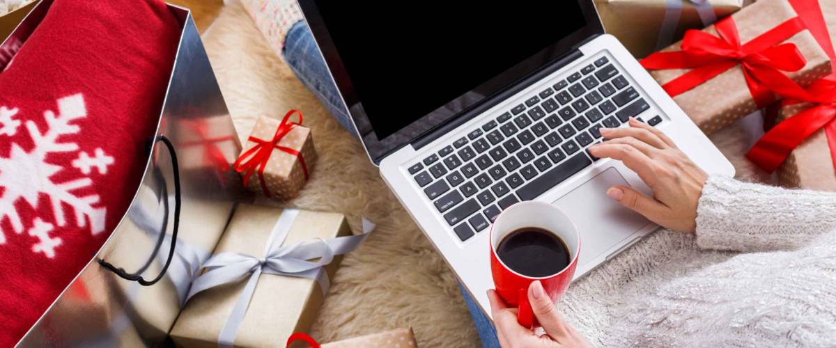Christmas online shopping above view. Female buyer makes order on laptop, copy space on screen. Woman buy presents, prepare to xmas, among gift boxes and packages. Winter holidays sales