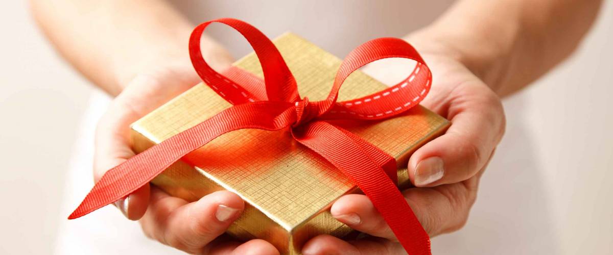 Woman holding a gift box in a gesture of giving.