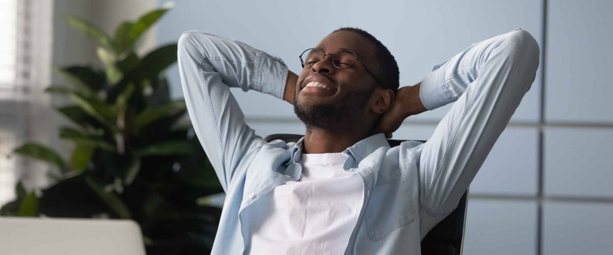 African businessman with hands behind head relaxing