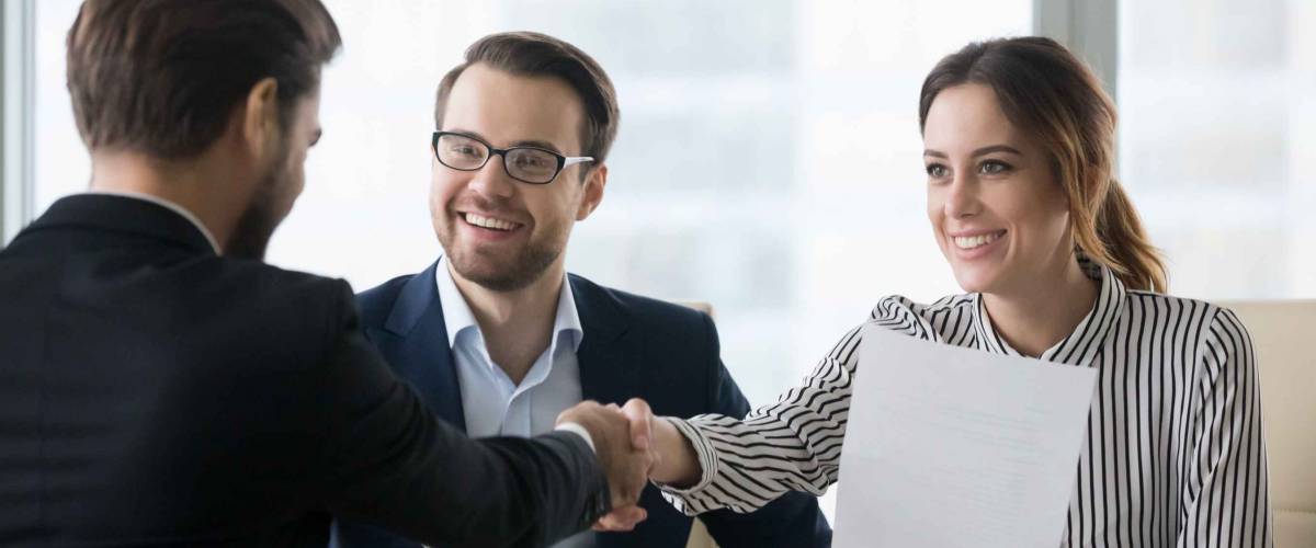 Happy employers shake hand of male job candidate