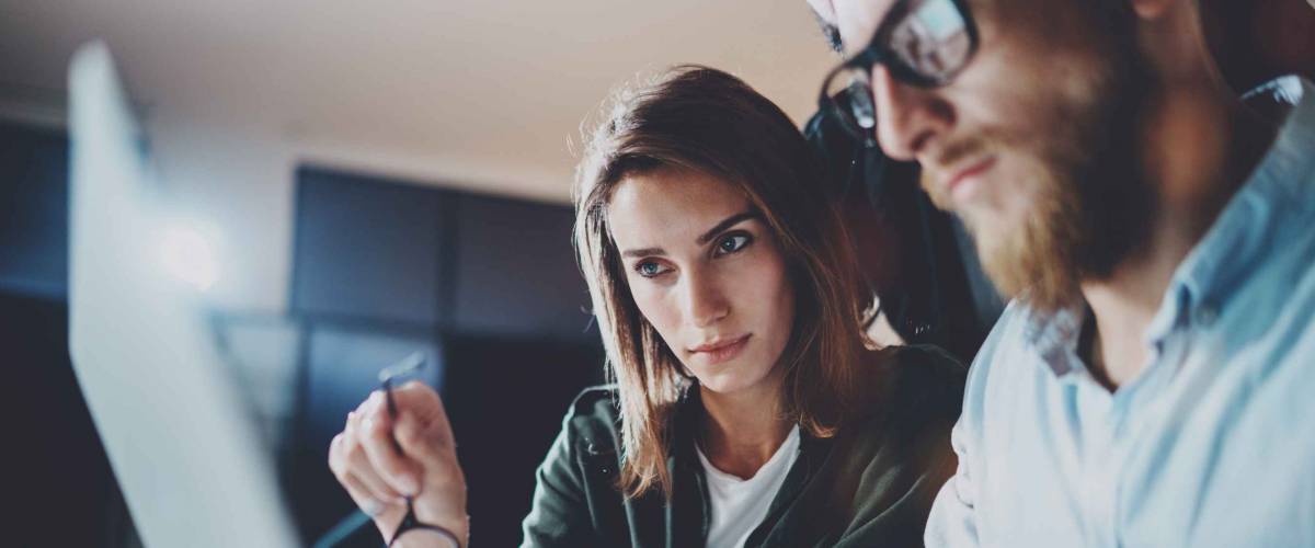 man and woman look at computer screen seriously