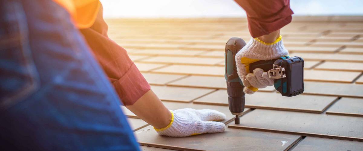Gray roof - Repair and Replace the House Roof with Handyman with Tools and Pprotective equipment. Stand on the Roof with the Ssky Background.
