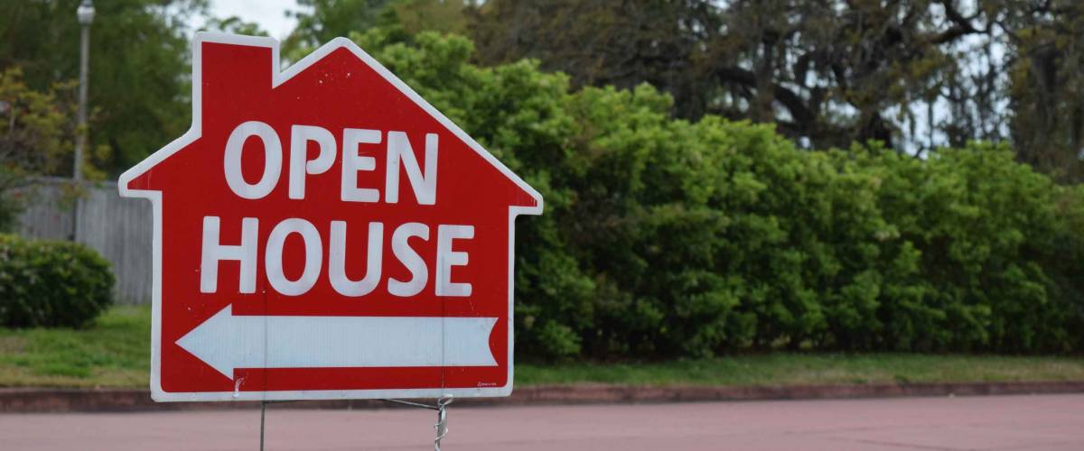 Real estate open house sign on lawn in nice suburban neighborhood.