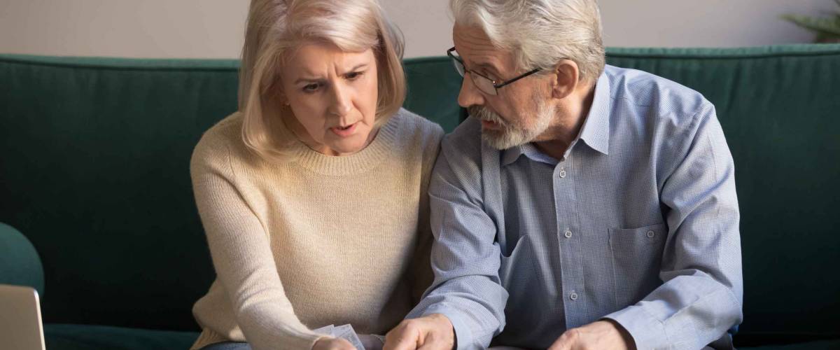 older couple sits on the couch and look intent while talking
